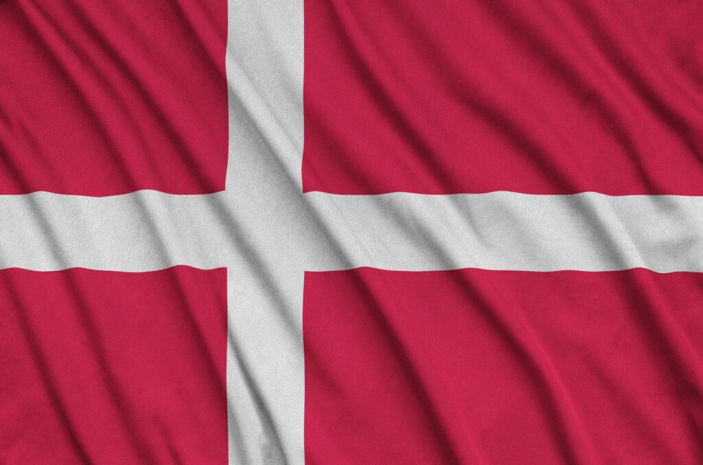 Die dänische Flagge ist auf einem Sportstoff mit vielen Falten abgebildet. Sportmannschaft winkt mit Fahne