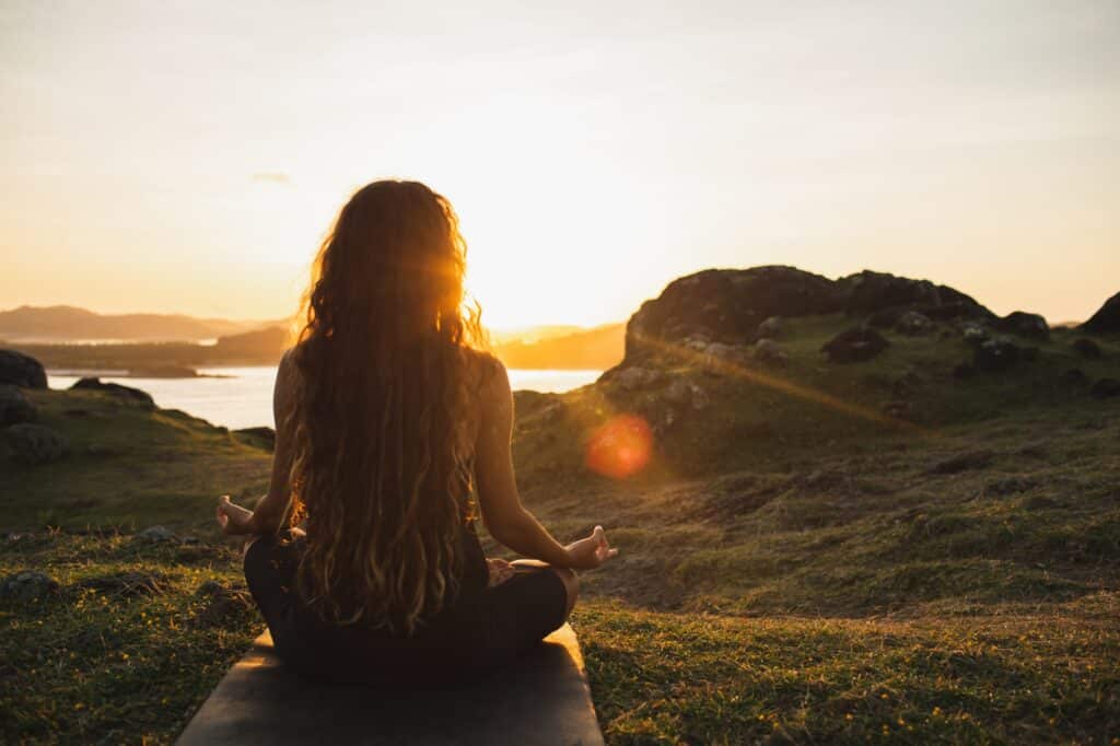 Frau meditiert Yoga allein bei Sonnenaufgang Berge. Blick von hinten. Reisen Lebensstil Geist